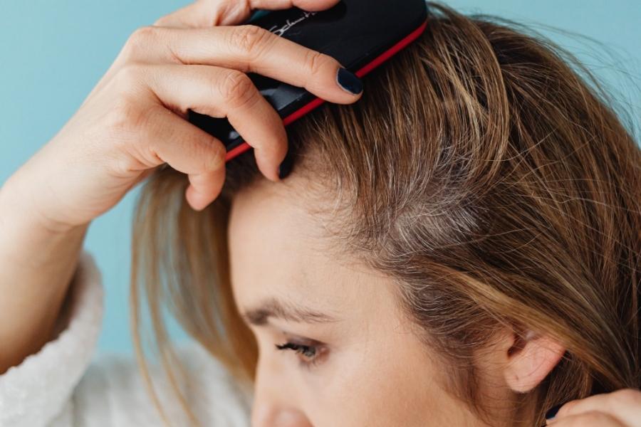 Woman performing DIY scalp detox treatment with massage device at home