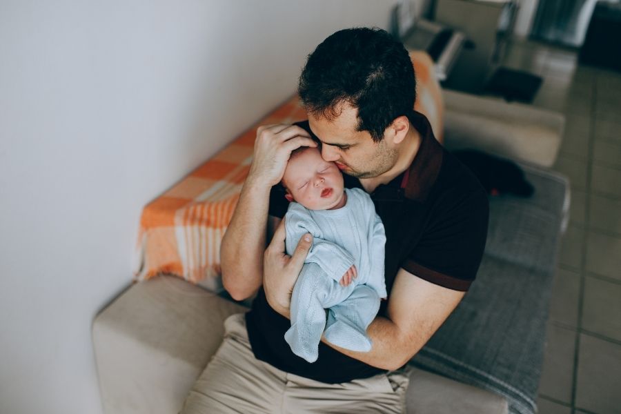 Father practicing gentle baby sleep techniques while holding newborn in comfortable home setting