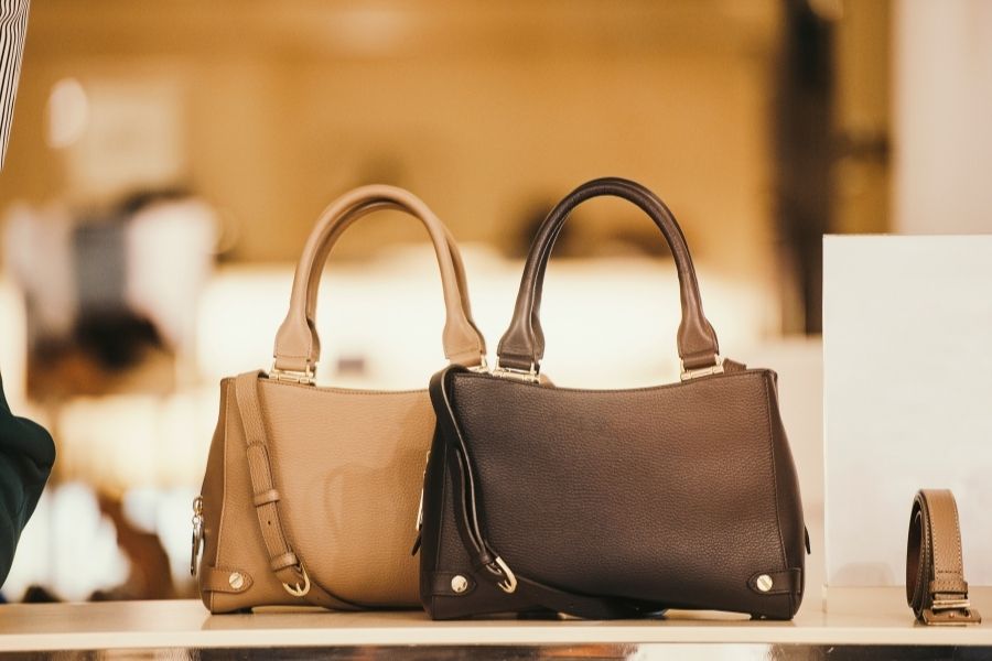 Woman carries red luxury handbag with gold hardware in urban setting