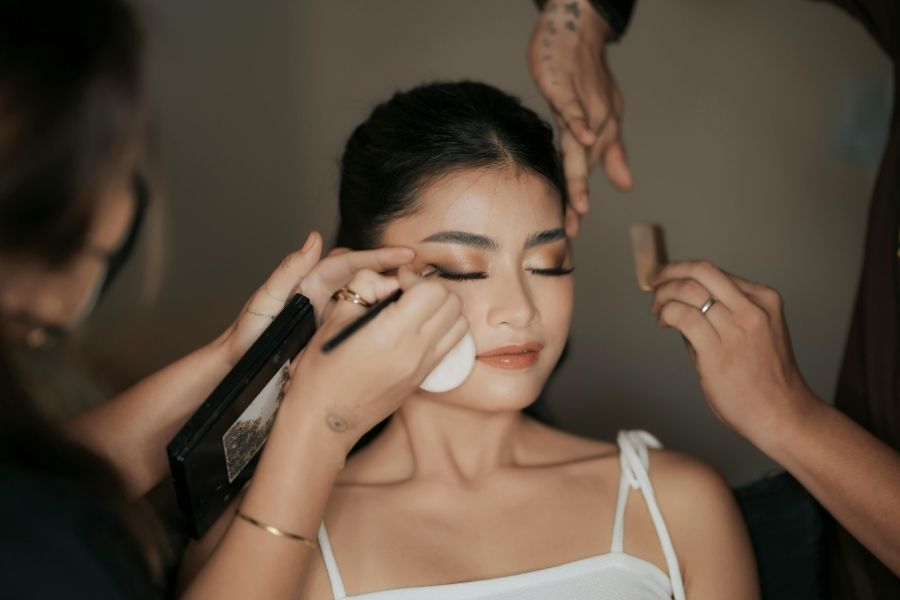 Professional makeup artist applying contouring stick to model's face during beauty session