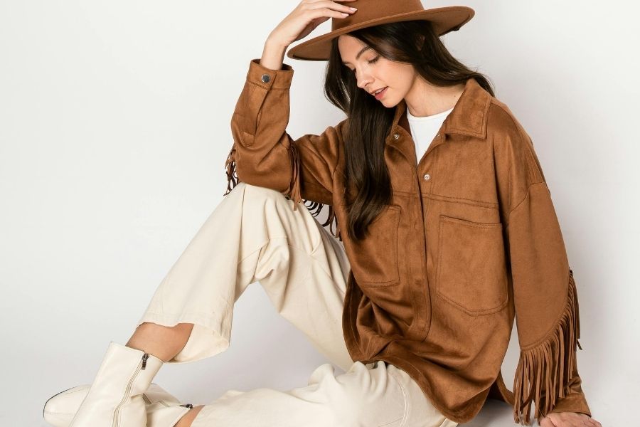 Woman wearing brown suede fringe jacket with cream pants demonstrating rules for outfits coordination