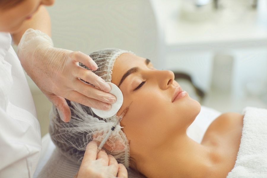 Professional administering cosmetic injection treatment showing Botox vs dermal fillers procedure technique