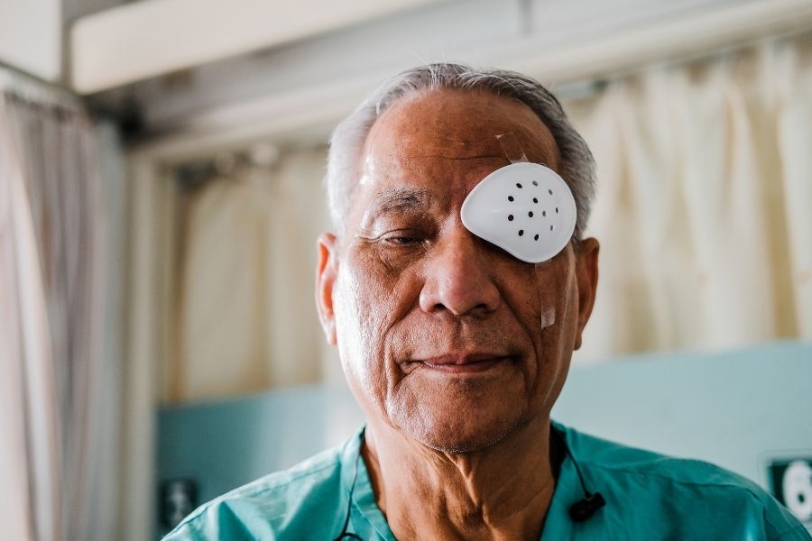 Senior man wearing eye patch in medical setting demonstrating importance to protect eye health through treatment