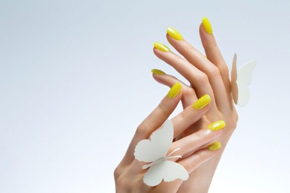 Trending nail art in bright yellow with textured finish and white butterfly decorations