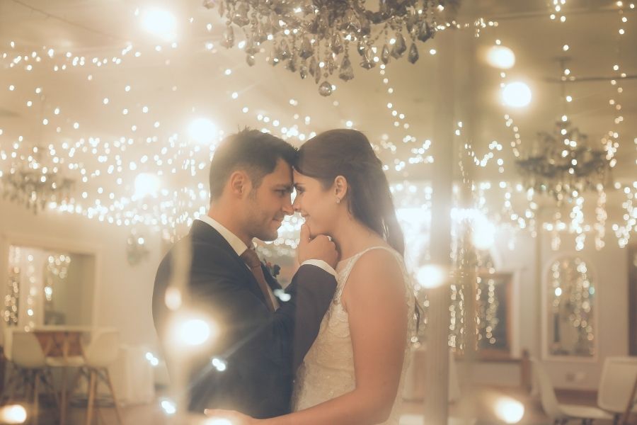 Bride and groom showcasing wedding trends 2025 with romantic fairy lights and elegant indoor setting