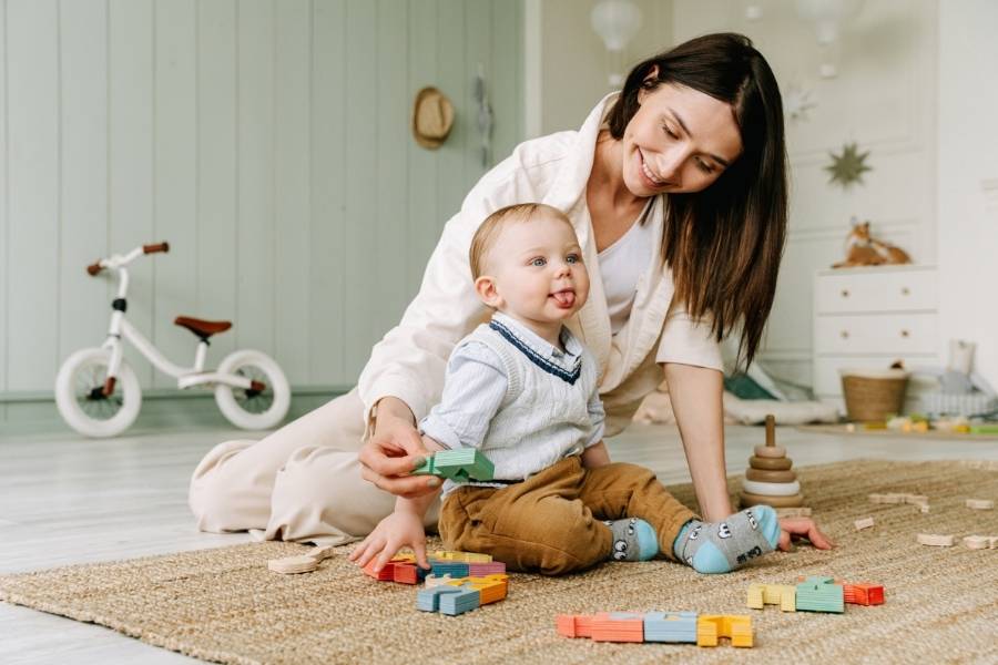 Mother playing with baby showing healthy baby development through interactive play with colorful blocks