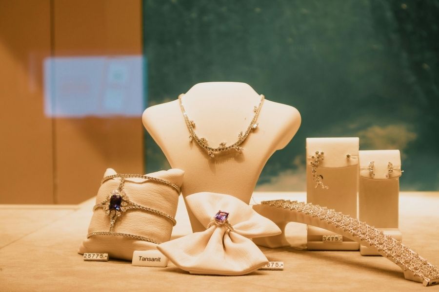 Elegant jewelry store display featuring fashion jewelry with gold chains, bracelets and earrings on neutral backdrop