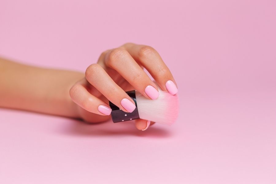 Trending nail art in soft pink shades with geometric black accent design on pink background