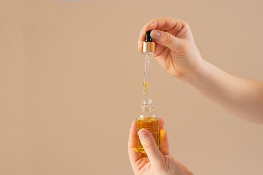 Hand applying castor oil for eyelashes from dropper bottle for natural lash growth treatment