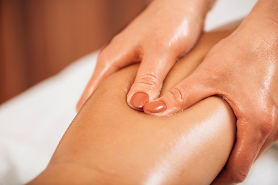 Professional therapist performing lymphatic drainage massage on client's leg with gentle circular motions