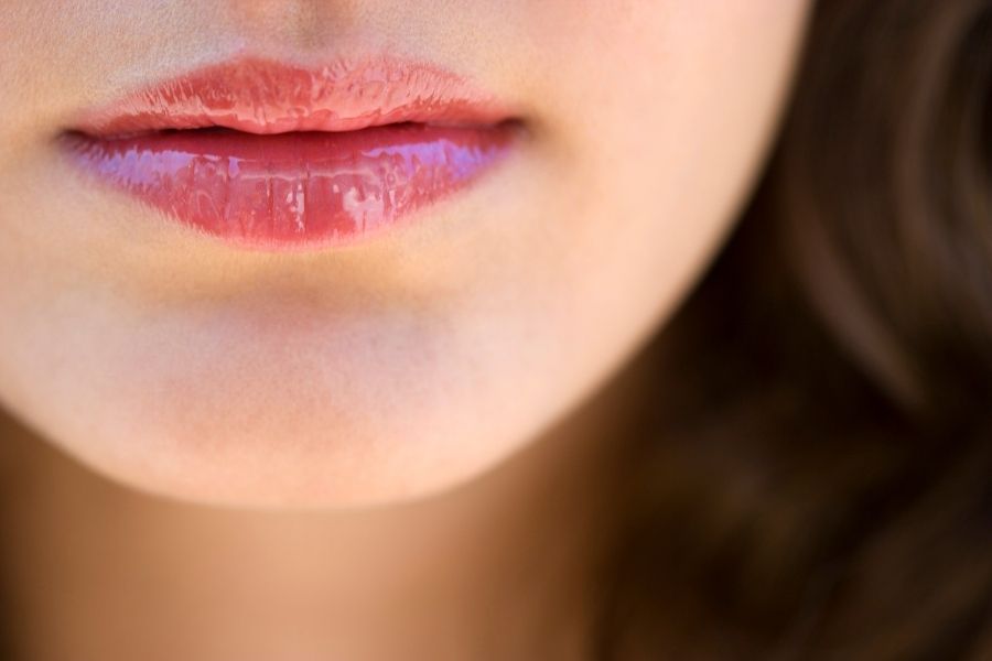 Woman wearing glossy coral long-wearing lipstick with natural makeup look