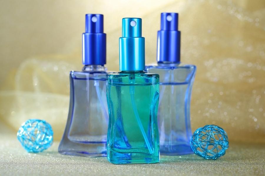 Collection of blue travel-size perfume bottles with decorative elements on golden background