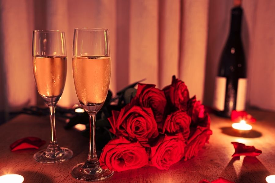Romantic Valentine's Day date night setup with champagne glasses, red roses, and candlelight