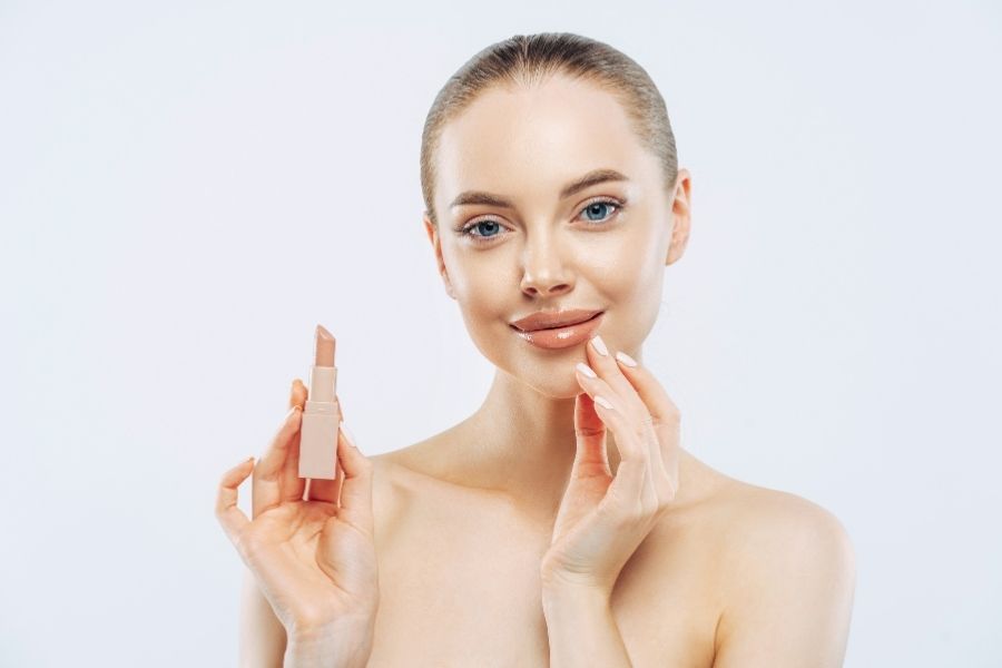 Professional beauty product shots featuring woman applying nude lipstick against clean background