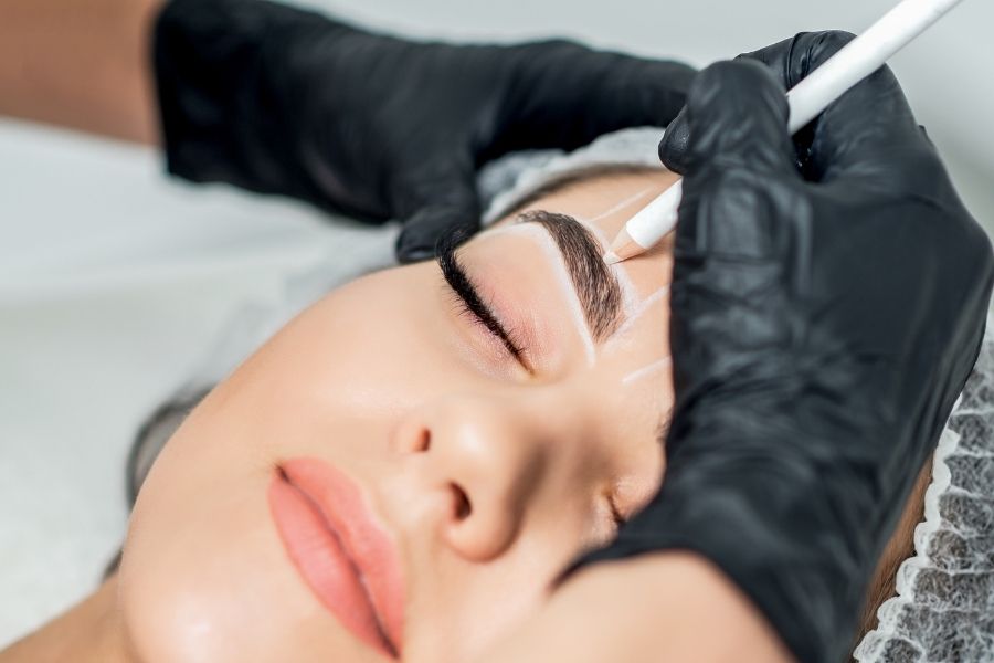 Professional brow mapping consultation with client lying comfortably during eyebrow analysis session