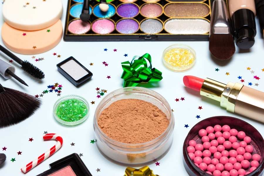 Festive Christmas party makeup products with colorful eyeshadow palette and holiday decorations