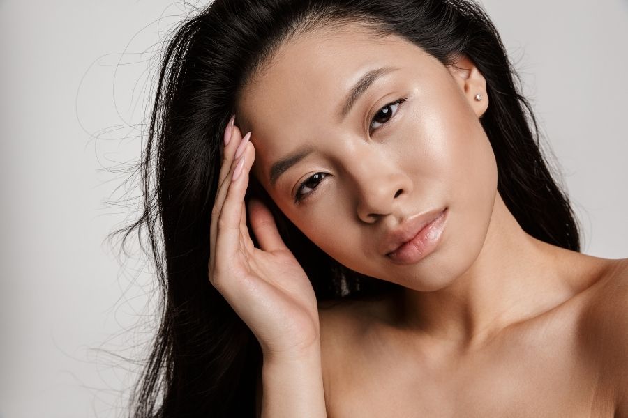 Asian woman with natural glowing skin demonstrating color analysis for warm undertones