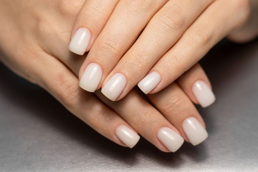 Elegant hands showing professional dip powder manicure with glossy nude finish