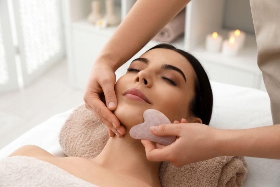 Professional gua sha facial massage treatment with rose quartz stone at spa