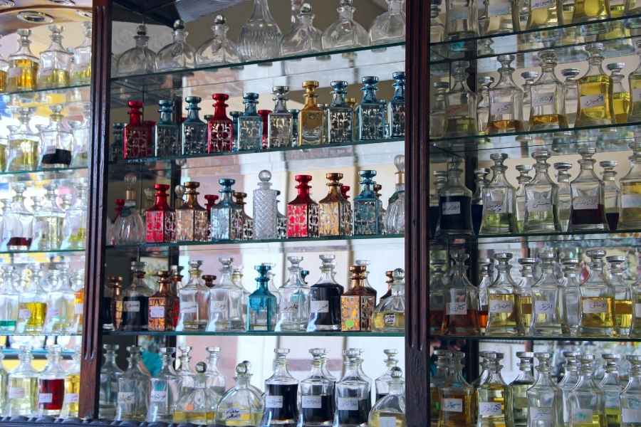 Antique glass display cabinet showcasing proper perfume storage with colorful vintage bottles
