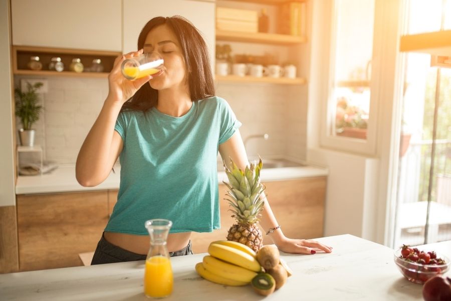 Woman enjoying healthy morning drink as part of quick beauty routines in bright kitchen