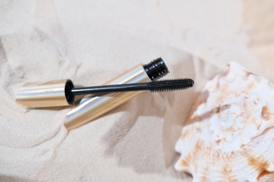Luxurious waterproof mascara with silver tube and black wand displayed on marble surface